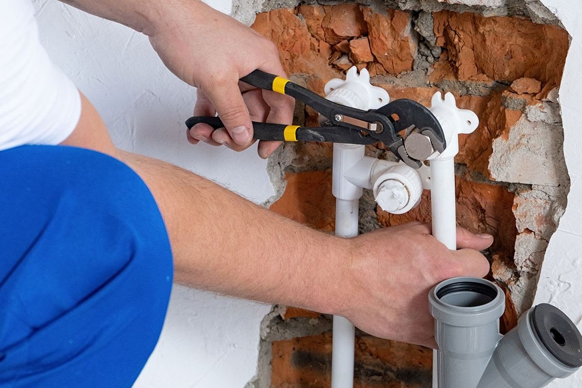 Técnico reparando una fuga en tubería de agua empotrada en muro
